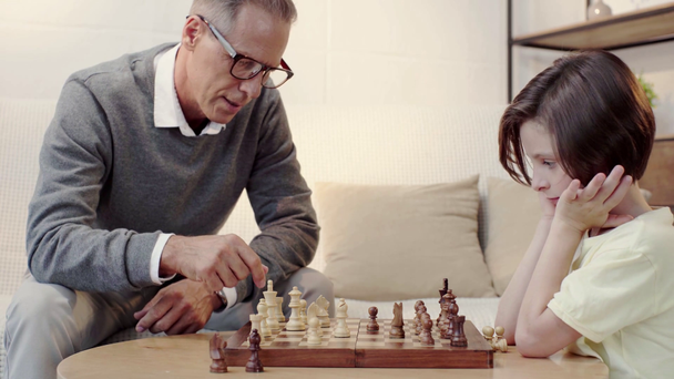дедушка учит внука играть в шахматы в гостиной
 - Кадры, видео