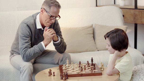Dědeček a vnuk hrát šachy v obývacím pokoji - Záběry, video