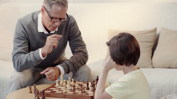 Dědeček a vnuk hrát šachy v obývacím pokoji - Záběry, video
