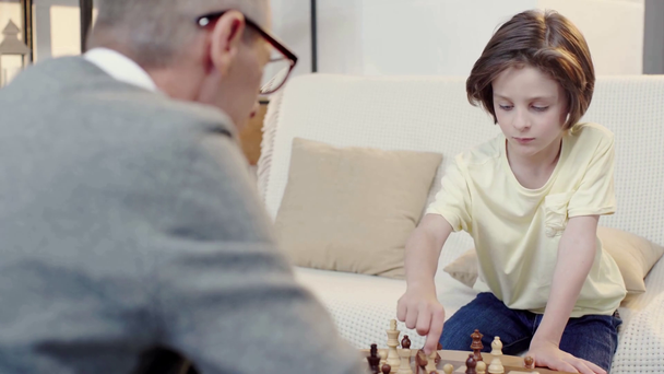 Дедушка и внук играют в шахматы в гостиной
 - Кадры, видео
