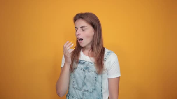 Молодая женщина в белой футболке, на оранжевом фоне показывает эмоции
 - Кадры, видео