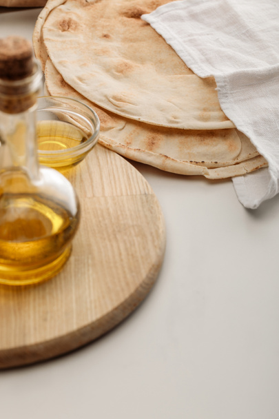 lavash bread covered with towel near cutting board with oil on white surface - Photo, Image