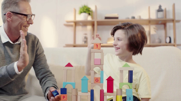 grandfather and grandson playing with building blocks and giving high five - Footage, Video
