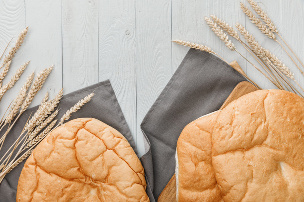 vista superior de pão lavash na toalha perto de picos de trigo na superfície de madeira branca
 - Foto, Imagem