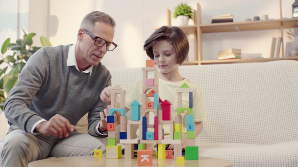 happy grandfather and grandson playing with building blocks and giving high five - Imágenes, Vídeo