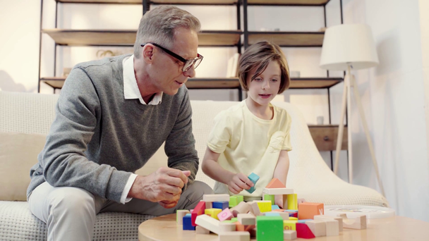 grandfather and grandson playing with building blocks together in living room - Video, Çekim