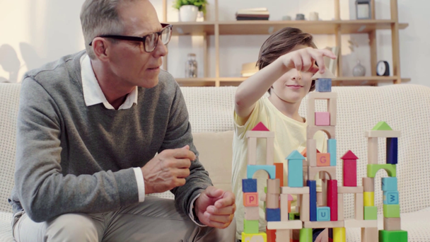 szczęśliwy dziadek i wnuk przytulanie i zabawy z bloków konstrukcyjnych - Materiał filmowy, wideo