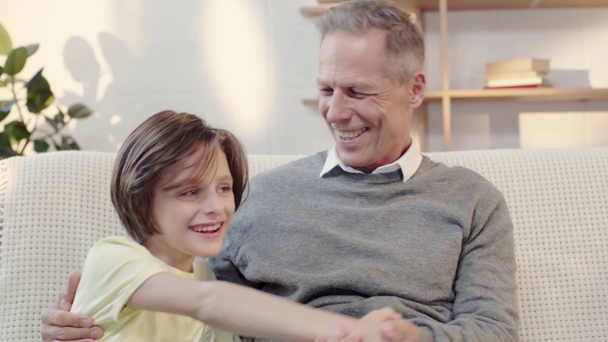 παππούς και εγγονός γέλιο και αγκάλιασμα στο σαλόνι - Πλάνα, βίντεο