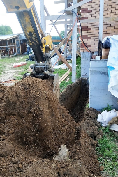 Der Bagger gräbt einen kleinen Graben im Hof aus. - Foto, Bild