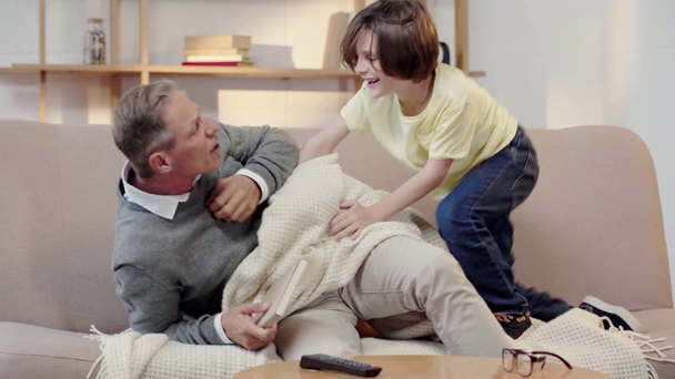 grandfather punish naughty grandson with book in living room - Filmagem, Vídeo