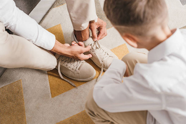 自宅で靴ひもを結ぶ息子を教える父の部分的な見解 - 写真・画像