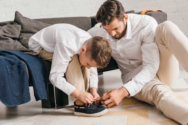 father teaching son to tying shoelaces at home - Foto, imagen