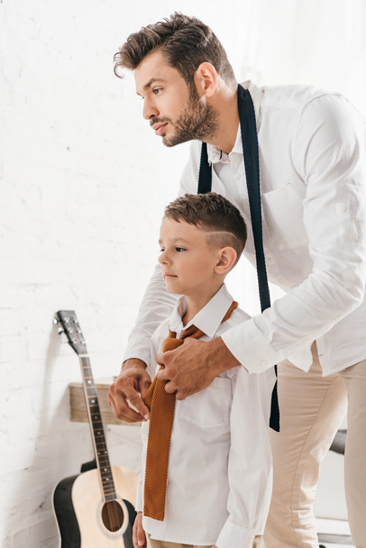 бородатый отец помогает сыну с галстуком дома
 - Фото, изображение
