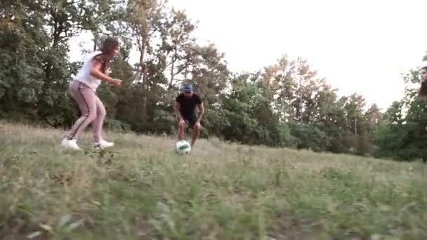 ein Kind mit Eltern und Familienfreunden spielt einen Ball auf einer Waldlichtung. - Filmmaterial, Video