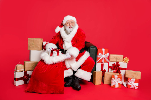 Portrait of nice cheerful cheery generous fat bearded man St Nicholas packing preparing fairy miracle orders winter december holly jolly isolated over bright vivid shine red background - Foto, imagen