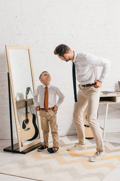 full length view of son and father in formal wear standing near mirror and looking at each other - Fotoğraf, Görsel