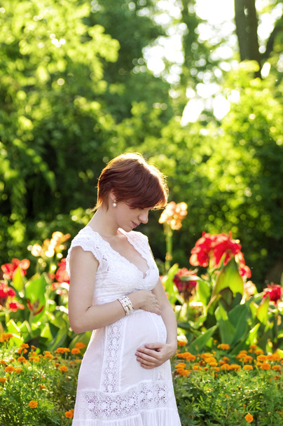 όμορφη έγκυο γυναίκα μέσα σε καταπράσινο κήπο - Φωτογραφία, εικόνα