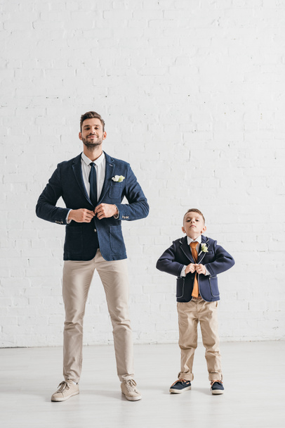 full length view of father and son in jackets with boutonnieres  - Foto, immagini