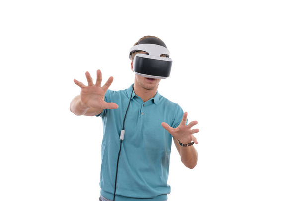 Kaukasischer Junge spielt mit Virtual-Reality-Brille und trägt ein blaues Poloshirt vor weißem Hintergrund - Foto, Bild