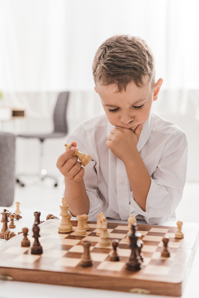 evde satranç oynayan beyaz gömlekli dalgın çocuk - Fotoğraf, Görsel