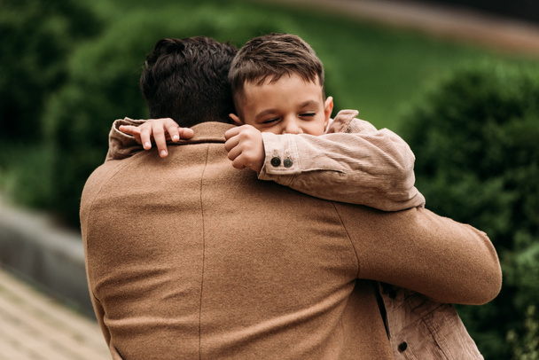 visão traseira do pai abraçando o filho na rua no dia de outono
 - Foto, Imagem