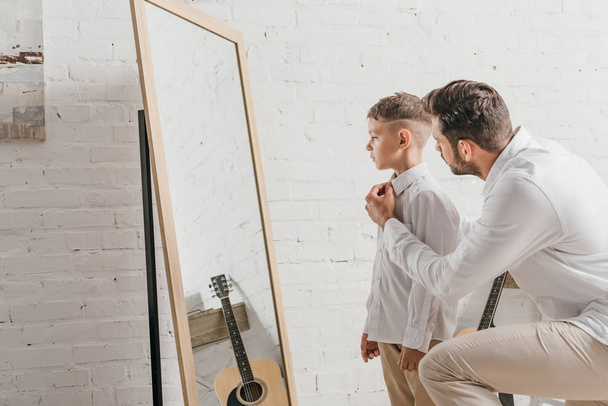 father helping son to get dressed near mirror - Fotoğraf, Görsel