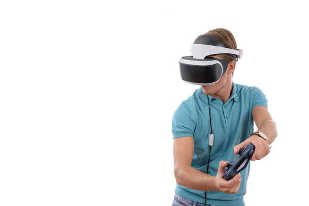 Garoto caucasiano brincando com óculos de realidade e controle de console virtual vestido com uma camisa de pólo azul isolada em fundo branco
 - Foto, Imagem
