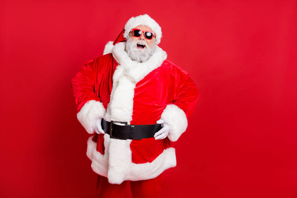 Portrait of his he nice attractive cheerful cheery positive bearded Santa having fun enjoying leisure dream vacation present gift isolated over bright vivid shine red background - 写真・画像