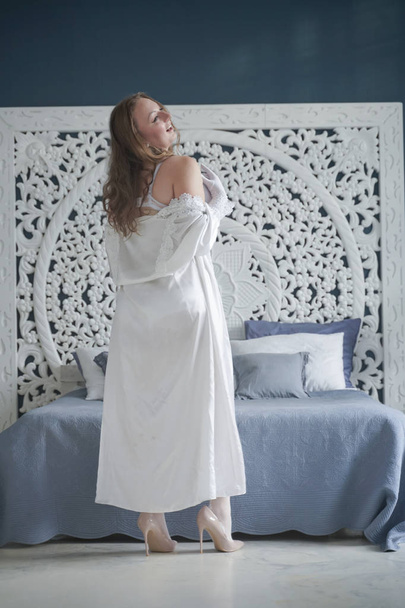 seksuele plus size bruid meisje in witte lingerie in de slaapkamer alleen. Mollige vrouw in kant ondergoed met korset en kousen alleen - Foto, afbeelding