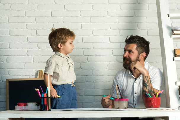 Family team, the father is engaged with his son drawing. A stylish bearded man and his little son. Responsible parent, art for teaching, home education. - Photo, Image
