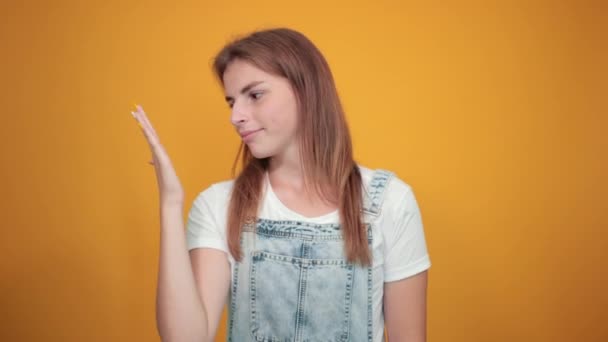 Fiatal nő visel fehér póló, több mint narancssárga háttér mutatja érzelmek - Felvétel, videó