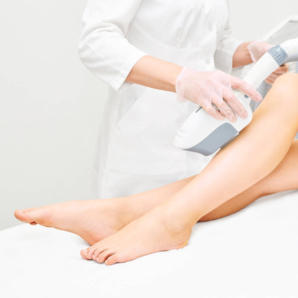 Laser ipl device in doctor hand. Woman body hair removal. Perfect epilator. Cosmetology leg technology - Foto, afbeelding
