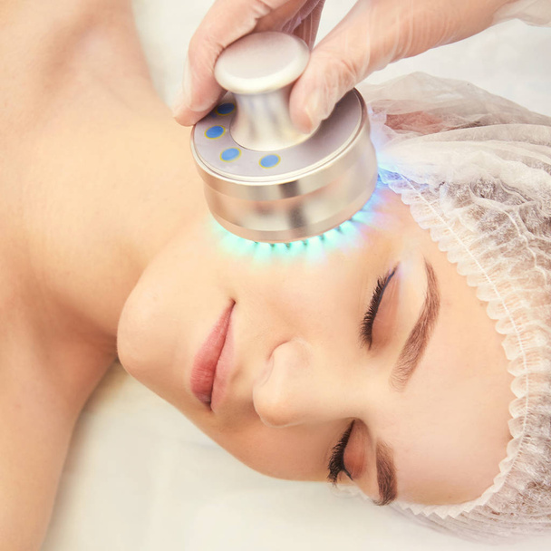 Light infrared therapy. Cosmetology head procedure. Beauty woman face. Cosmetic salon device. Facial skin rejuvenation - Фото, зображення