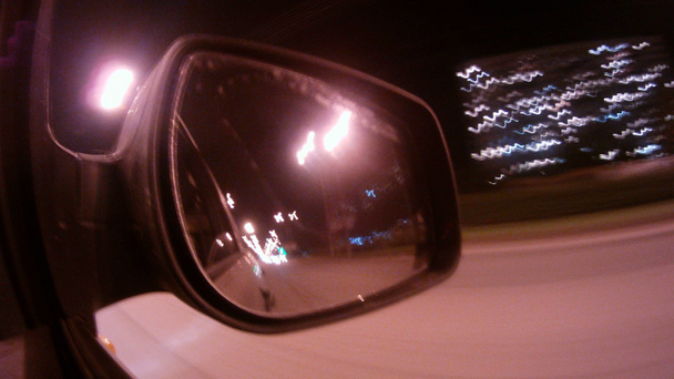 v zrcadle automobilu odrážejí světla noční město - Záběry, video