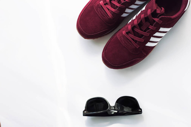 Burgundy sneakers on a white background with nature light shadows. - Photo, Image