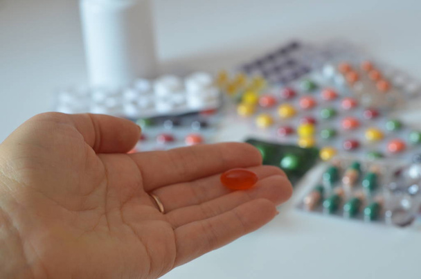 selective focus Medicine pills or capsules in hand, palm or fingers. Drug prescription for treatment medication. Woman, young female, person taking vitamin, painkiller, antibiotic - Photo, image