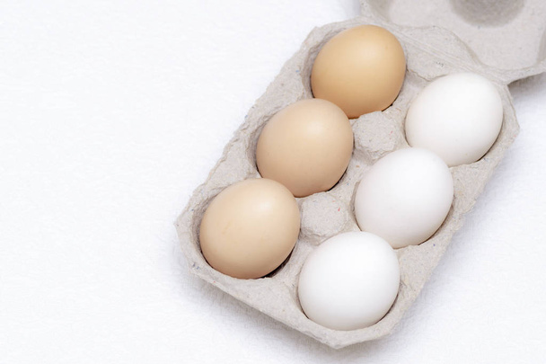 段ボールトレイに白い卵3個と茶色の卵3個 - 写真・画像