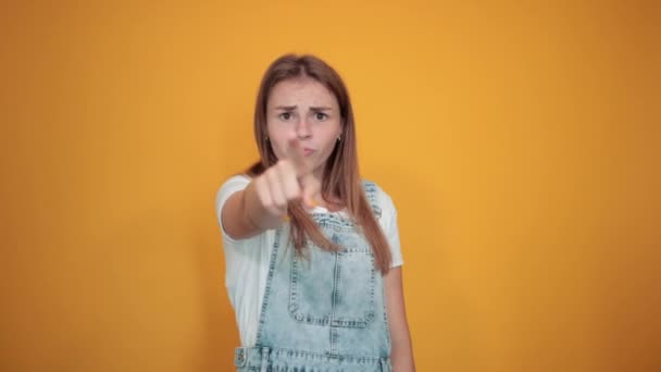 Mujer joven vistiendo camiseta blanca, sobre fondo naranja muestra emociones
 - Metraje, vídeo