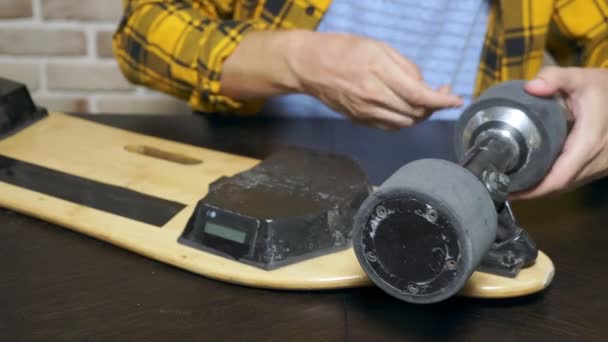 close-up.Man hands who repair a broken electric skateboard. unscrews the wheels - Footage, Video