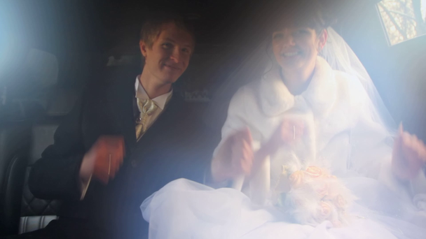 man en vrouw in trouwjurken zitten in limousine samen - Video