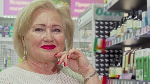 ドラッグストアで買い物をするエレガントな高齢女性のクロップドショット - 写真・画像