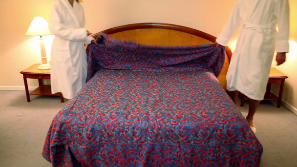 Hombre con mujer en albornoces vienen al dormitorio y se quitan la bata de la cama
 - Metraje, vídeo