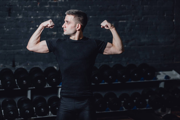 Young man in the gym. Healthcare. Lifestyle. A sexy man dressed in a black T-shirt. Caucasian Bodybuilder is nourished body. - Fotografie, Obrázek
