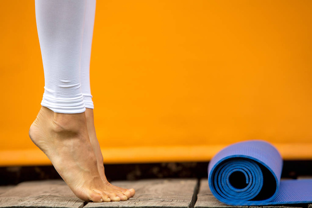 Sporty yoga girl with yoga mat wearing sport clothes over orange background - Foto, Bild