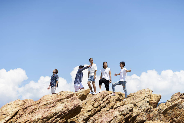 молоді азіатські дорослі чоловіки, що стоять на вершині каменів
 - Фото, зображення