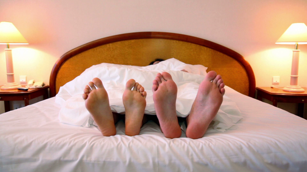man en vrouw slapen in bed onder deken op kamer met lampen aan elke kant - Video