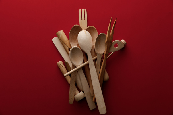 top view of eco-friendly wooden spoons, fork and kitchenware on red background - Foto, imagen