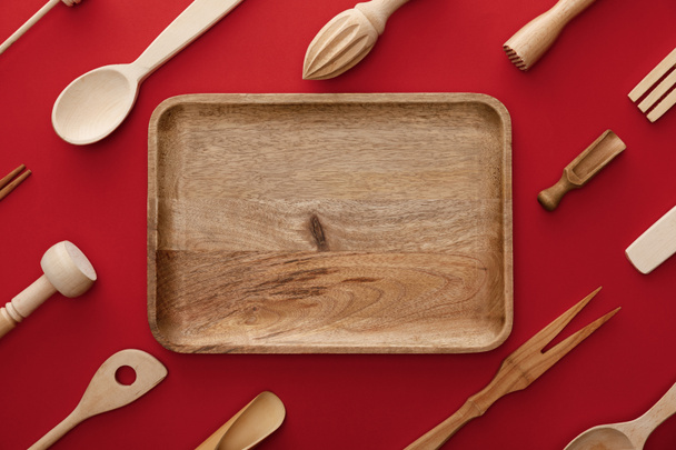 top view of natural rectangular  wooden dish on red background with kitchenware - Fotoğraf, Görsel