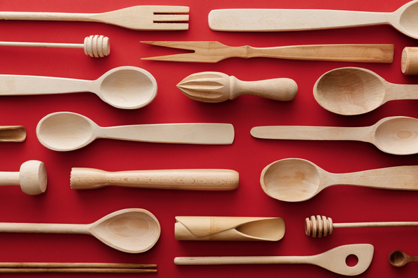 top view of natural wooden spoons and kitchenware on red background - Foto, afbeelding