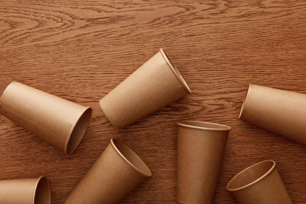 top view of empty paper cups on brown wooden background - Foto, imagen